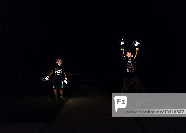 Boys playing with sparklers at night