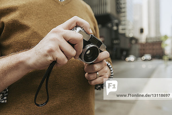 Mittendrin ein Mann  der eine Kamera hält  während er auf einer Straße in der Stadt steht