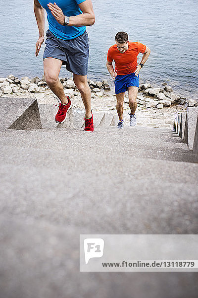 Hochwinkelaufnahme von männlichen Athleten  die auf Treppen am Strand laufen