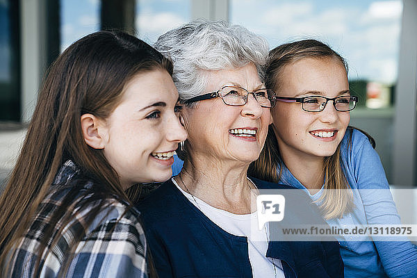 Happy grandmother and granddaughters looking away on porch