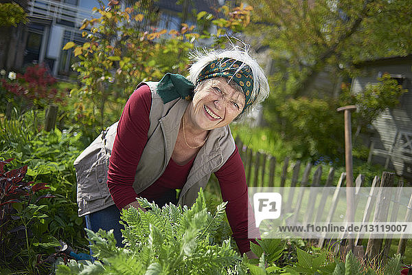 Porträt einer fröhlichen älteren Frau bei der Gartenarbeit im Hinterhof