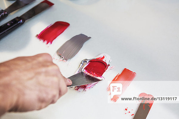Beschnittenes Bild einer Hand  die auf dem Tisch des Workshops Farben mischt