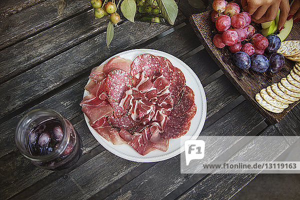 Hochwinkelansicht von Fleisch und Früchten auf einem Holztisch