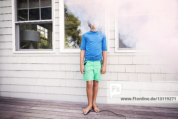 Junge steht inmitten von Rauch vor dem Haus