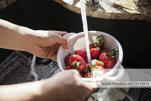 Ausgeschnittenes Bild von Händen  die Erdbeeren im Sieb waschen