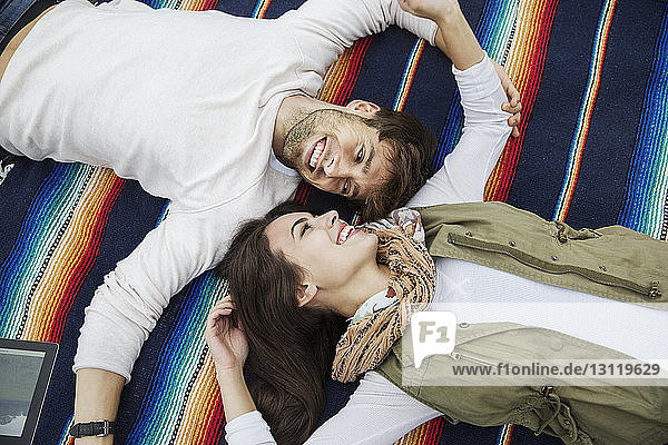 High angle view of loving couple looking at each other while lying on blanket