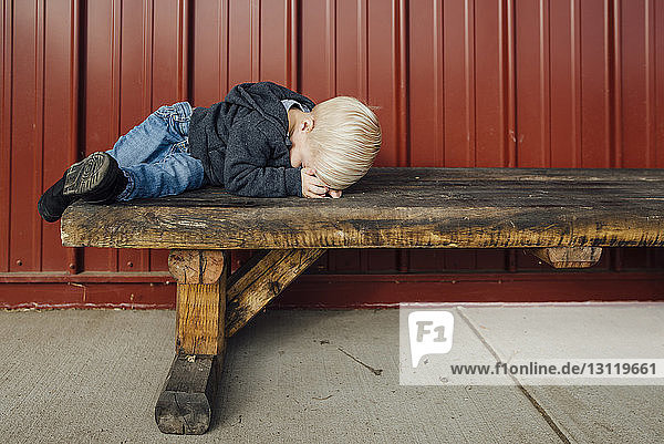 Junge in voller Länge auf Holzbank schlafend