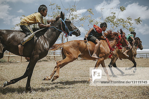 Seitenansicht von Kindern auf Rennpferden beim Pferderennen
