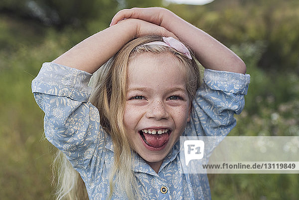 Porträt eines glücklichen Mädchens mit Händen auf dem Kopf im Park stehend