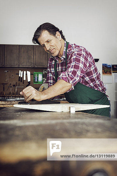 Lächelnder Mann sägt Holz in der Werkstatt