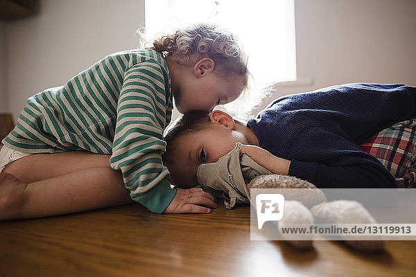 Side view of girl kissing brother on head at home