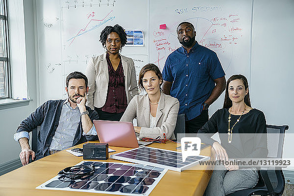 Portrait of business people by solar panel models on desk