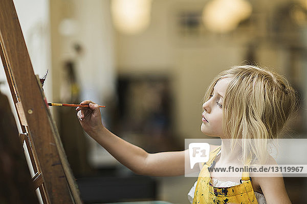Serious girl painting on canvas at home