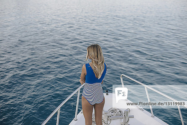 Rückansicht einer Frau  die Badebekleidung trägt  während sie auf einer Yacht auf See steht