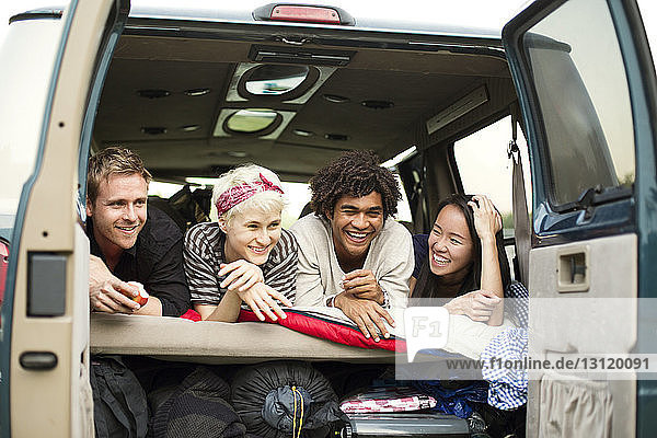 Happy friends lying in back of camping van