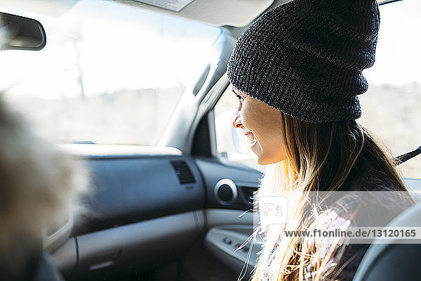 Lächelnde junge Frau sitzt während einer Autofahrt im Auto