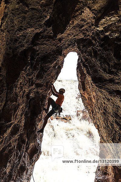 Seitenansicht eines Wanderers  der an einer Felsformation in der Wüste klettert