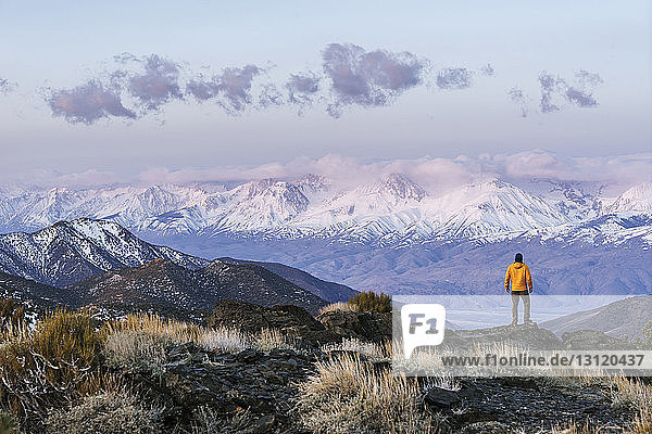 Rear view of hiker standing on mountain against sky