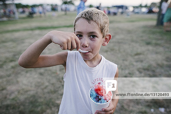Porträt eines Jungen  der auf dem Feld Crushed-Ice isst