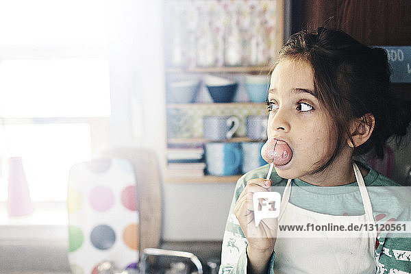 Thoughtful boy eating lollipop at home