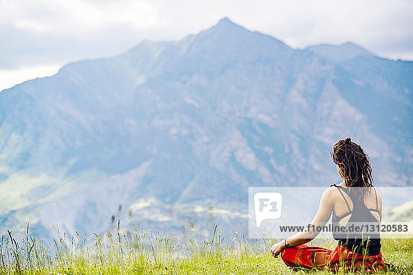 Rear view of woman doing yoga against mountains