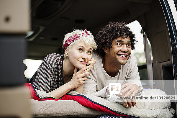 Smiling couple lying in back of camping van