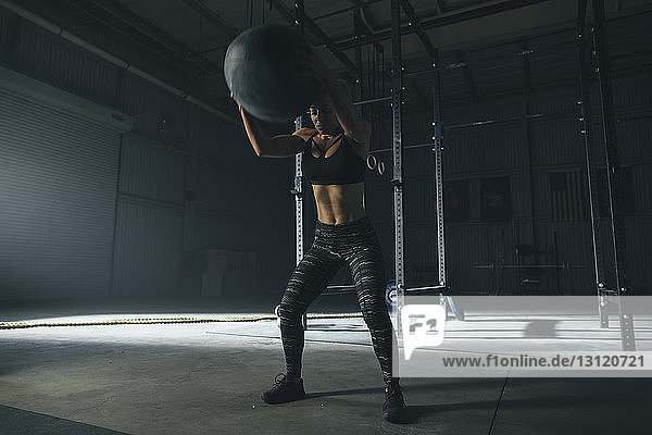 Female athlete exercising with fitness ball in gym