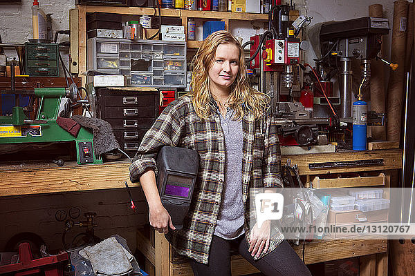 Porträt einer selbstbewussten Mechanikerin mit Schutzmaske in der Werkstatt