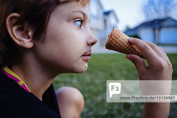 Seitenansicht eines Mädchens  das Eiswaffeln betrachtet  während es im Hof sitzt