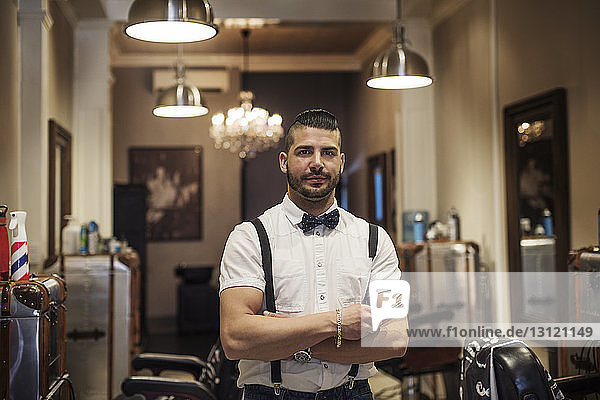 Portrait of barber with arms crossed standing in shop