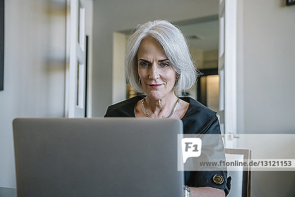 Seriöse Geschäftsfrau  die im Büro an einem Laptop-Computer arbeitet