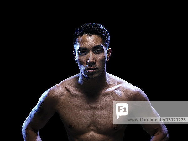 Portrait of confident kickboxer against black background