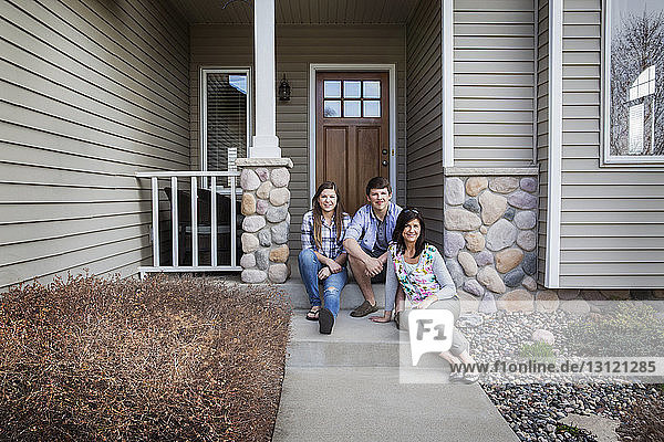 Porträt einer glücklichen Familie  die am Eingang des Hauses sitzt