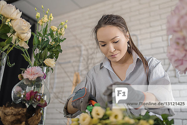 Floristinnen schneiden Blumen  während sie im Blumengeschäft arbeiten