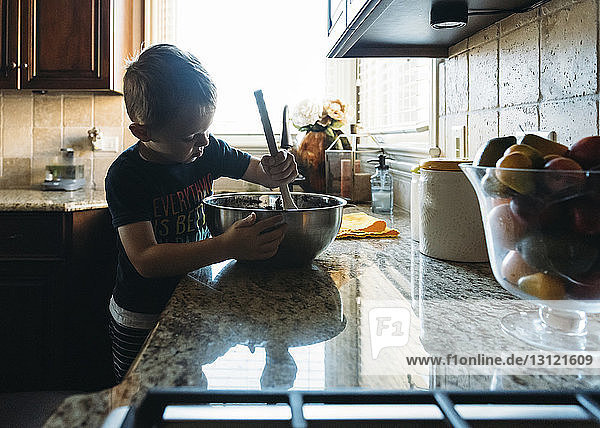 Junge mischt Essen  während er an der Küchentheke steht