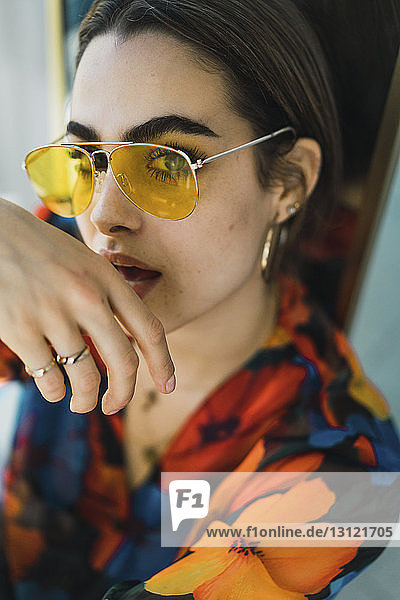 Porträt einer selbstbewussten jungen Frau  die zu Hause eine Sonnenbrille trägt