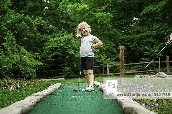 Porträt eines lächelnden Mädchens  das den Putter hält  während es auf dem Golfplatz steht