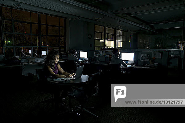 Geschäftsleute  die nachts in einem dunklen Büro arbeiten