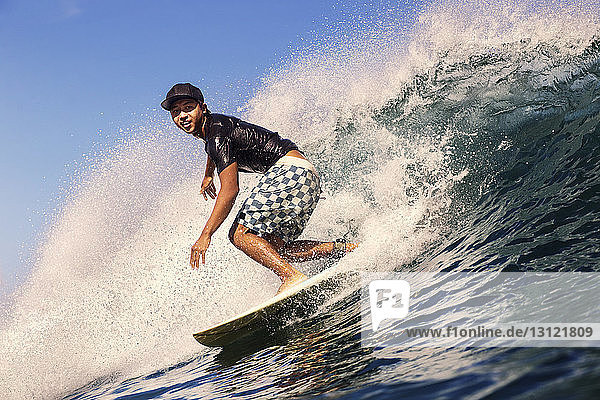 Young man surfing in sea against sky