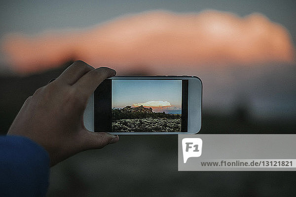 Geschnittene Hand einer Frau  die mit einem Smartphone Landschaft fotografiert