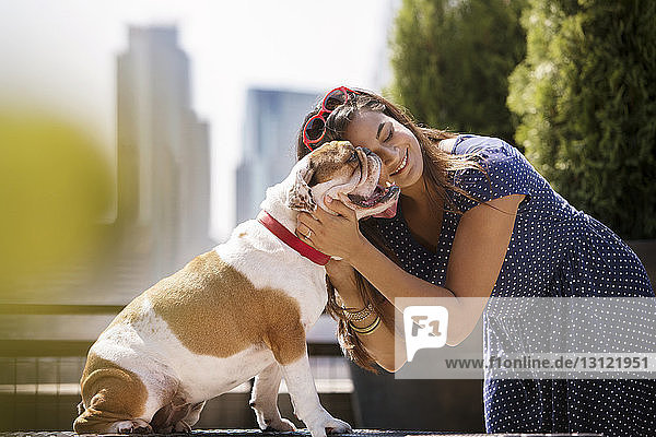 Lächelnde Frau mit Bulldogge an sonnigem Tag