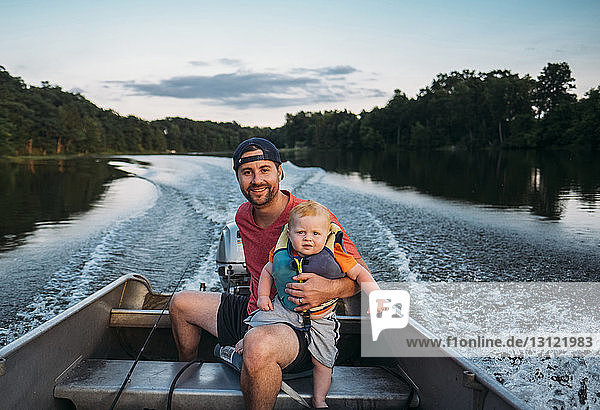 Portrait of father with son sitting in motorboat on lake
