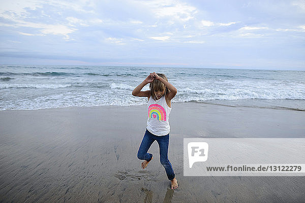 Mädchen in voller Länge spielt am Huntington Beach gegen den Himmel