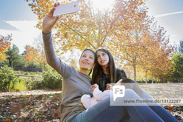Lächelnde Mutter mit Töchtern im Herbst im Park
