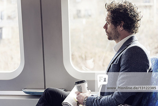 Seitenansicht eines Geschäftsmannes  der durch ein Zugfenster schaut