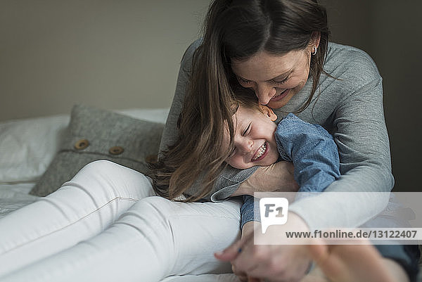 Happy mother playing with son on bedroom at home