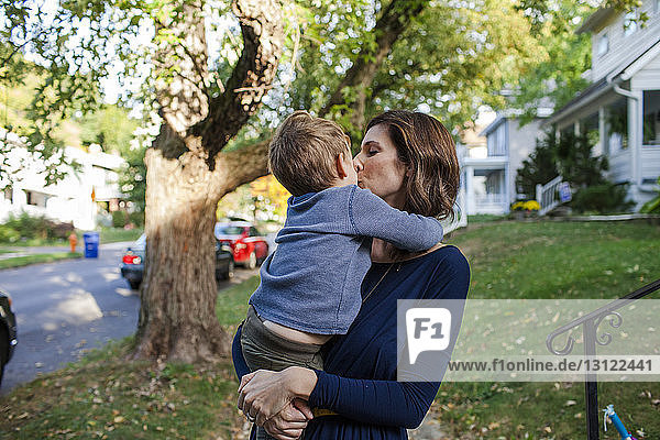 Mutter küsst Sohn  während sie an Bäumen steht