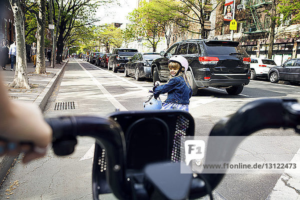 Girl looking at mother while riding bicycle on street