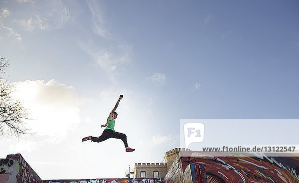 Niedrigwinkelansicht eines Stuntmanns  der über Gebäude gegen den Himmel springt
