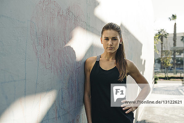 Porträt einer selbstbewussten Sportlerin  die im Freien an der Wand lehnt